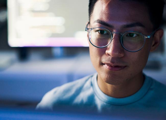 researcher at computer screen in a blue-lit environment