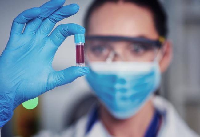 Scientist holds a vile of blood in gloved hand