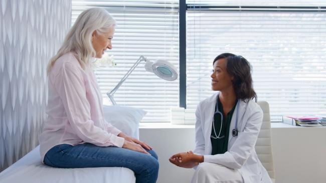 Doctor talking with mature female patient after medical exam in office. 