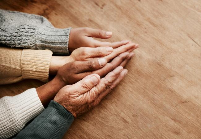 People across the age spectrum place their hands together.