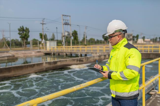 Environmental engineer takes notes at a wastewater treatment plant. 