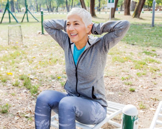 Woman exercises at an outdoor gym. 