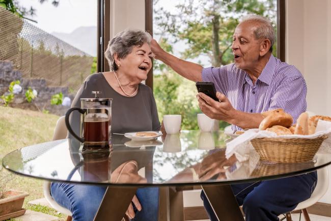 Older couple sitting at a table celebrating great news.