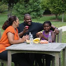 Family eating healthy snacks at a table outside.