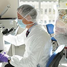 A surgical oncologist conduct research in the shared facility for cellular processing.