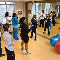 Women in a class working out with dumbbells in front of a mirror.