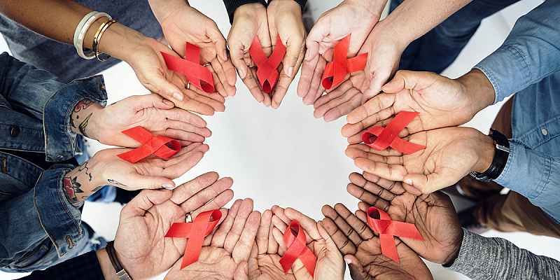 A group of racially diverse hands holding AIDS red ribbons