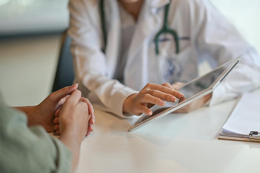 Image of a doctor showing a patient something on a tablet screen.