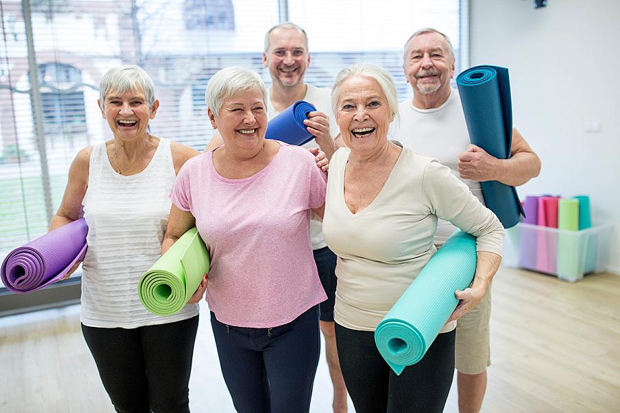 Group of happy seniors holding yoga mats