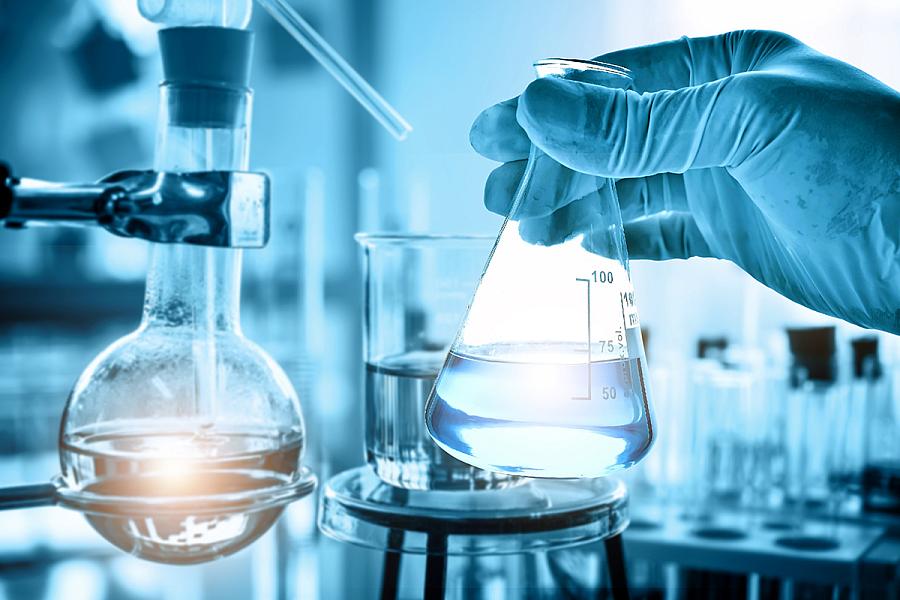 hand of scientist holding flask with lab glassware in chemical laboratory background