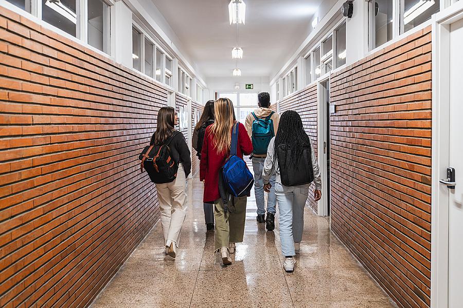 High school students walking down school hallway after class 