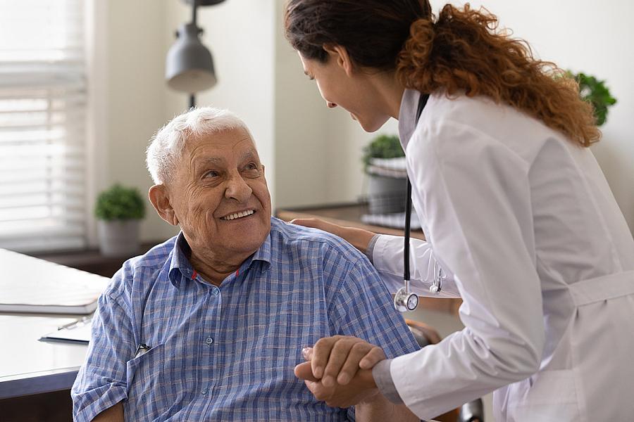 Nurse holding hand of smiling mature patient at meeting in hospital