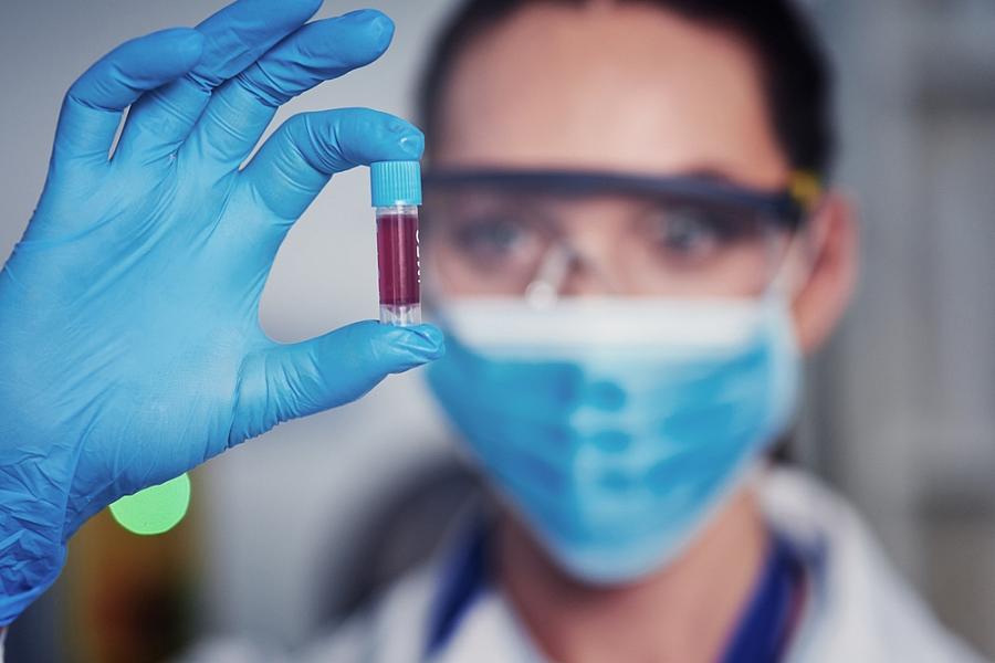 Scientist holds a vile of blood in gloved hand