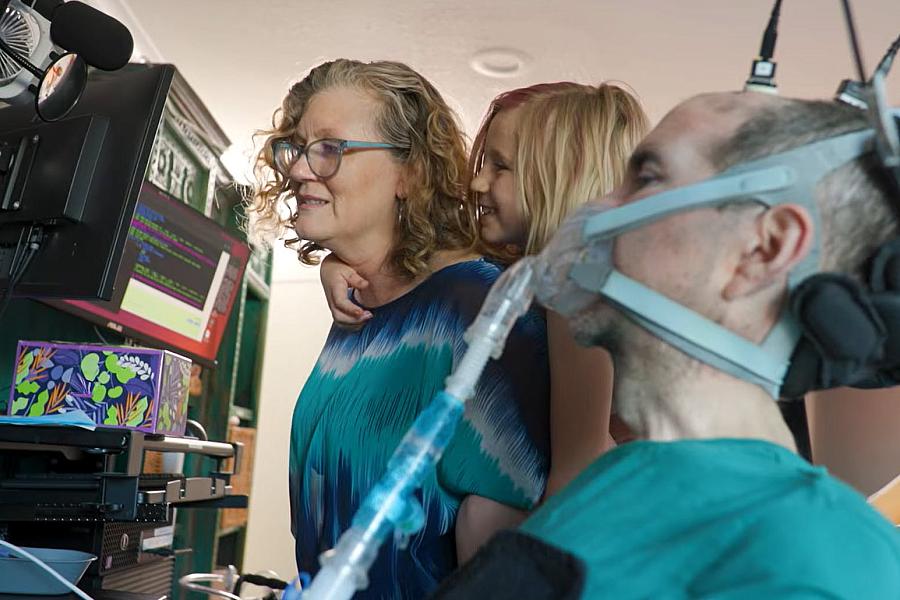 Harrell uses the brain-computer system with his wife and daughter alongside him in their home.