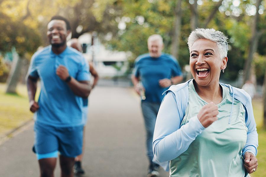 An older woman happily jogs outside with three other runners.