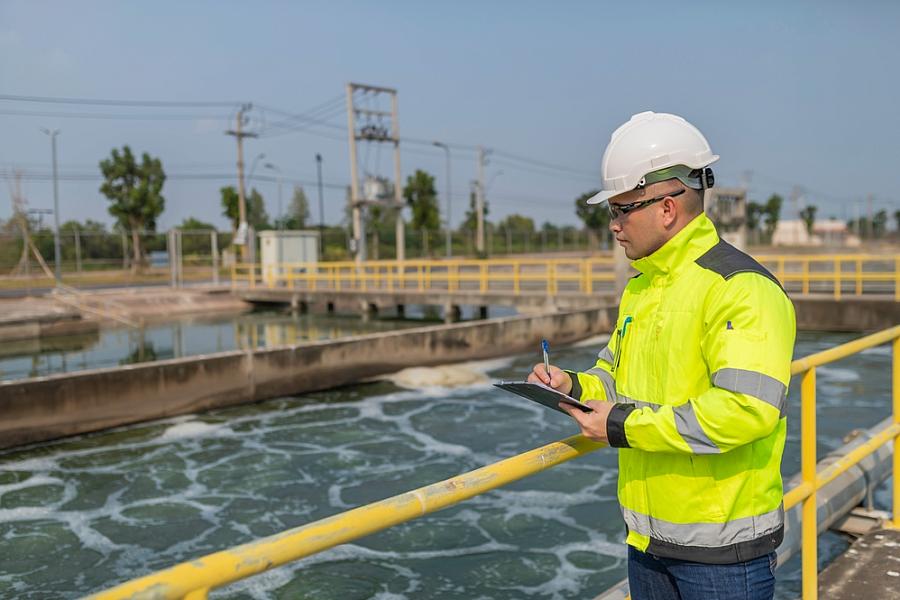 Environmental engineer takes notes at a wastewater treatment plant. 