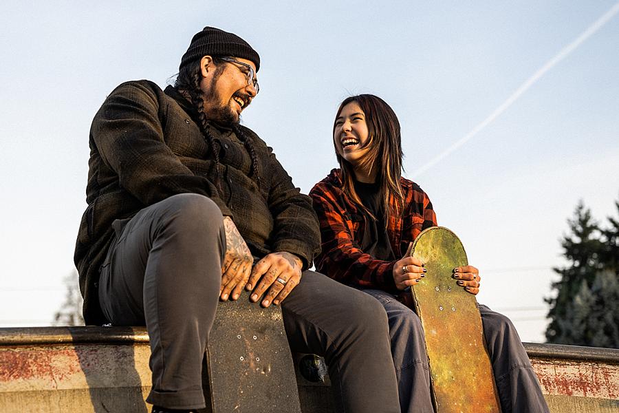 Two people sitting at the top of a ramp at a skate park