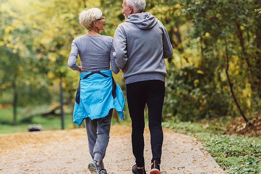 Cheerful active senior couple jogging in the park. Exercise together to stop aging. 
