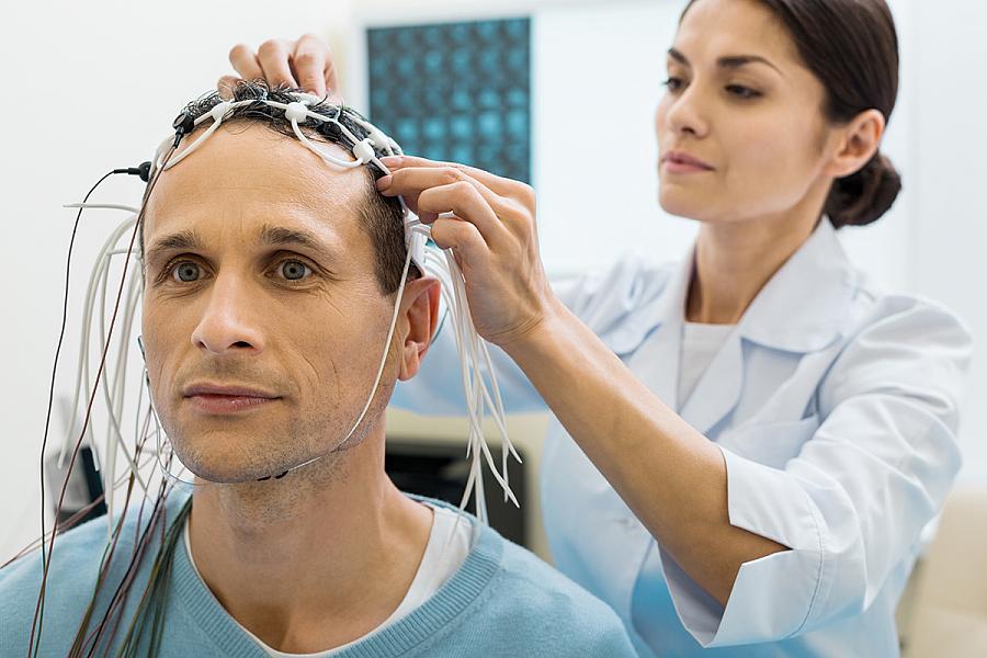 Doctor fixing electrodes on head of a patient 