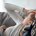 Upset depressed young woman lying on couch feeling strong headache migraine, sad tired drowsy teenager exhausted girl resting trying to sleep after nervous tension and stress, somnolence concept