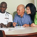 Photo of a doctor speaking with a patient and a family member.