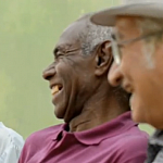 Video screenshot of three mature men talking together.