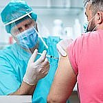 Medical technician administering vaccine to man's arm