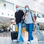 Couple walking through airport terminal pulling their luggage