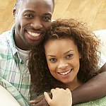 Close-up of a young black couple smiling at the camera.