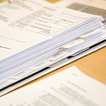 Binder with papers on office desk.