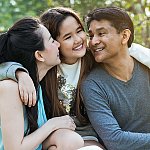 A couple sitting outside with their young daughter