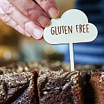 A close-up of a bakery employee labeling fresh brownies as gluten free