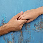 A close-up of two people holding hands over a distressed blue background