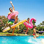 Kids jumping into a swimming pool with inflatable tubes