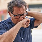 A mature man coughing