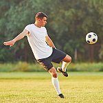 A man kicking a soccer ball on a field of grass