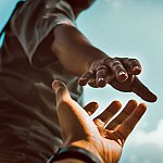 A close-up of a man reaching for someone's hand
