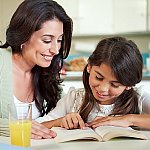 A woman and her young daughter reading a book together