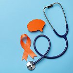 An orange awareness ribbon, paper brain cutout, and stethoscope on a blue background
