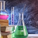 Beakers and books in front of a chalkboard