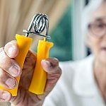 A close-up of a senior woman holding a hand gripper
