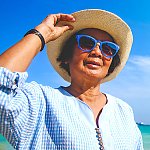 A senior woman wearing sunglasses and a hat outdoors