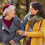 A senior woman and her caregiver walking outside