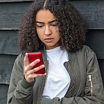 A teenage girl looking down at a cell phone