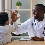 A male doctor high fiving a young boy