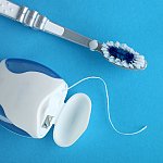 A toothbrush and dental floss on a blue background