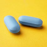 Two identical looking blue pills on a yellow background