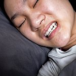 A young girl lying in bed and suffering from bruxism