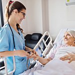 Nurse adjusting oxymeter on senior woman's finger