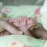 Preterm infant's hand holding an adult's fingers